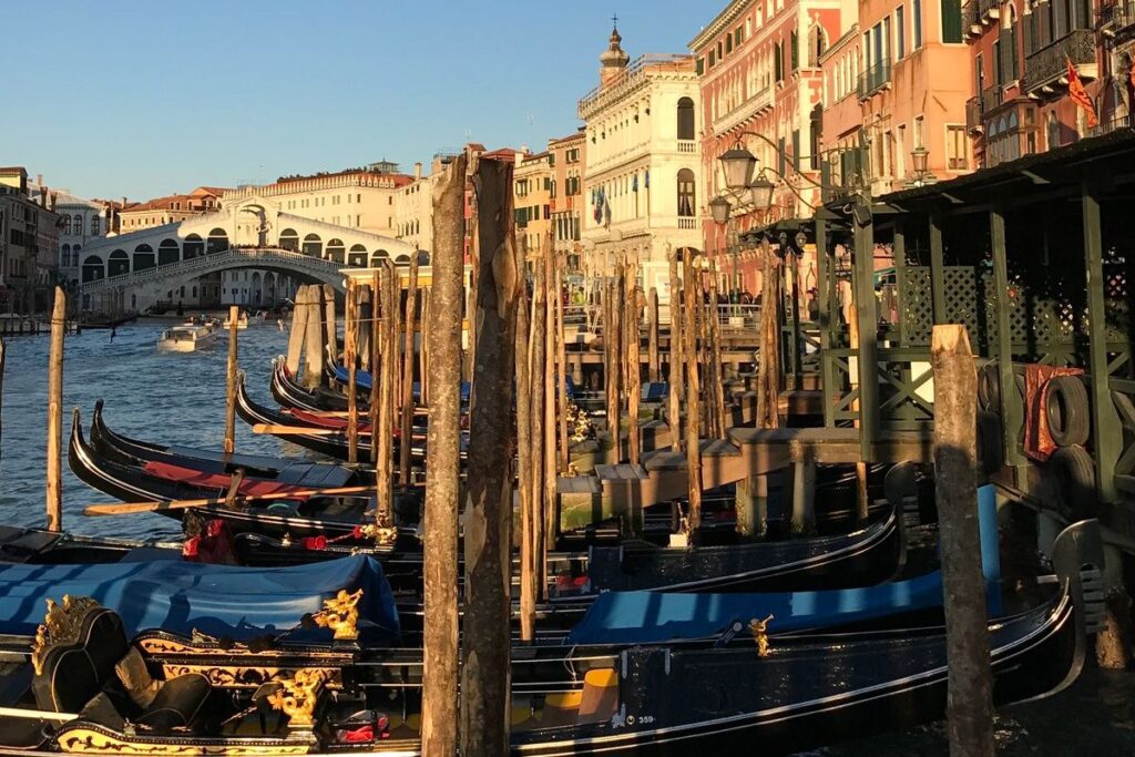 Gondole ormeggiate sul Canal Grande con il Ponte di Rialto sullo sfondo al tramonto